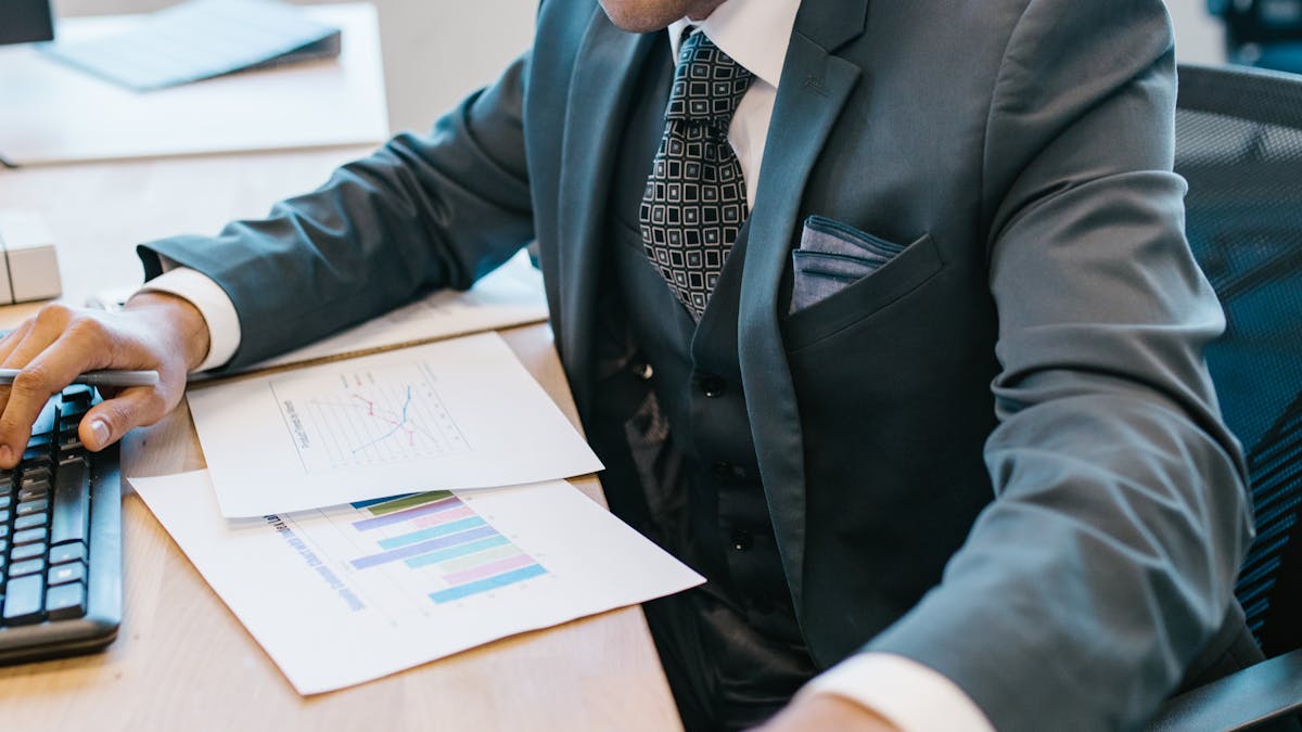 Indian businessman in suit at desk with financial reports and charts &mdash; GST review